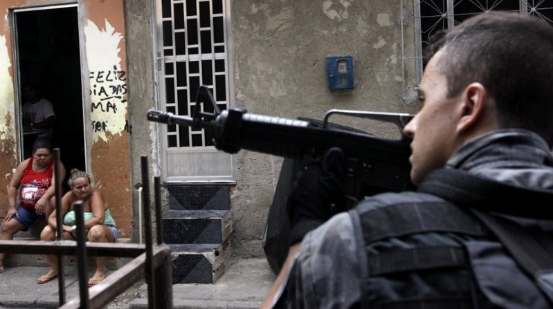 Policial anda pelas ruas e checa moradores para garantir a segurança durante uma operação no complexo de favelas da Maré no Rio de Janeiro (Ricardo Moraes/ Reuters)